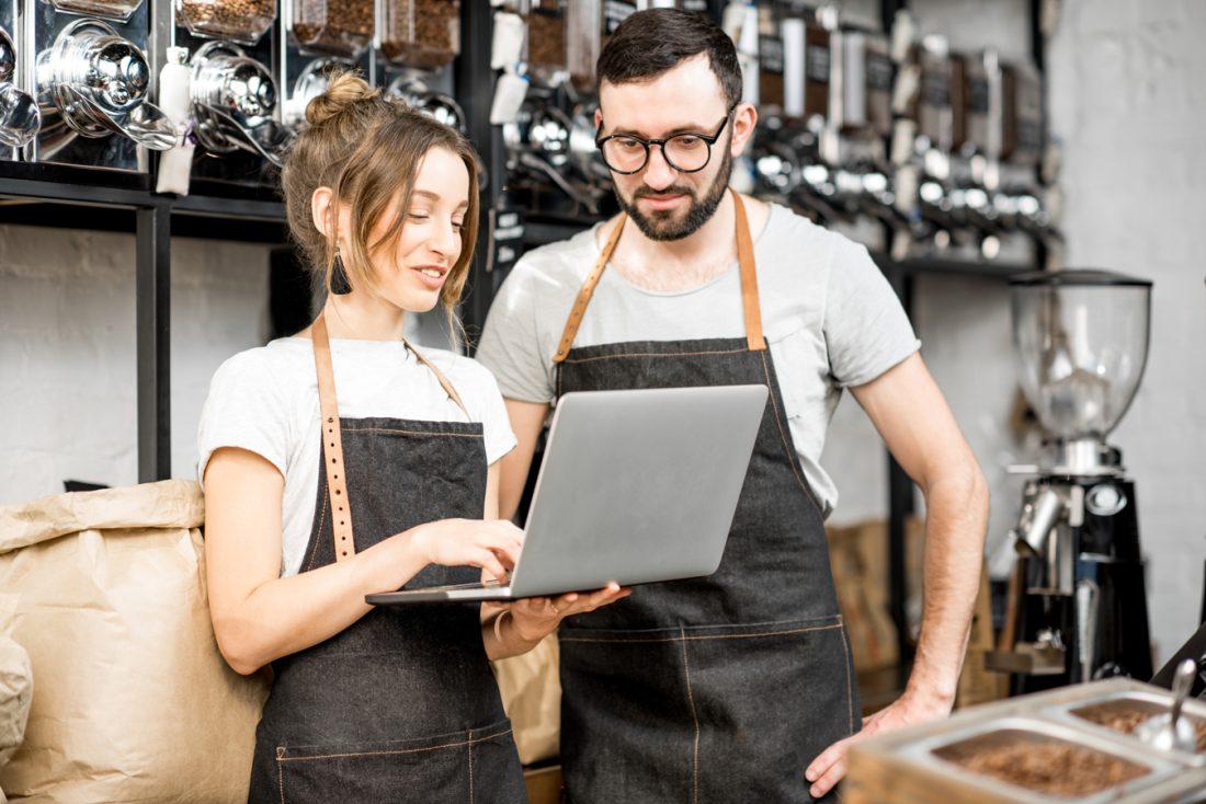 Coffee Store Owners Working With Laptop Indoors
