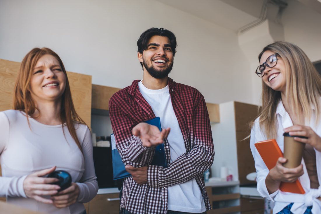 Group Of Cheerful Coworkers Talking In Workspace