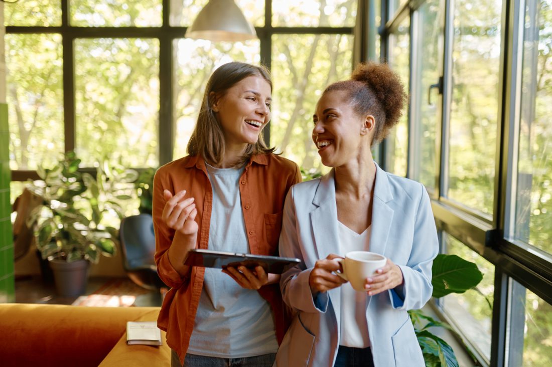 Happy Cheerful Coworkers Chatting At Workplace