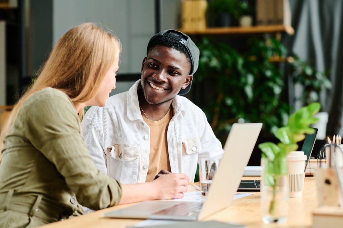 Young Smiling African American Businessman Listening To Female Colleague