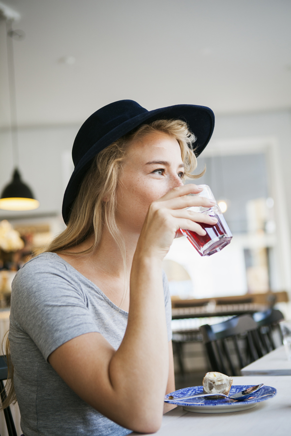 Young Woman Having Drink At Table In Restaurant