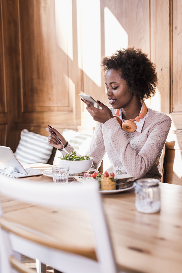 Young Woman Using Cell Phone And Tablet In A Cafe